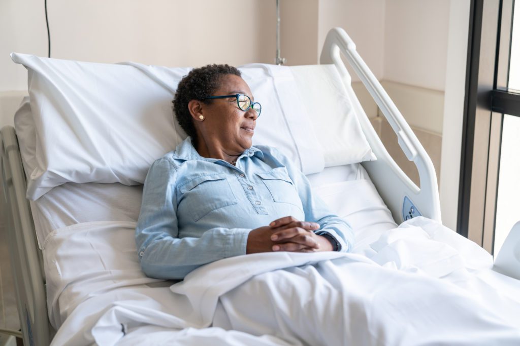 An adult patient lying down on bed hospitalized looking away to the window