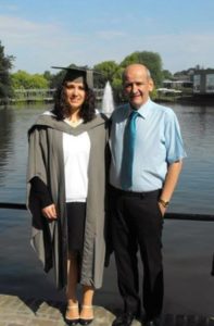 Derek and one of his daughters smiling for a photograph in front of a lake for her graduation