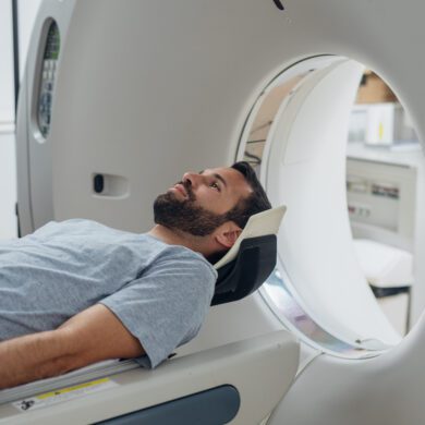 Man laying down on his back in a hospital gown, waiting to go into an MRI machine