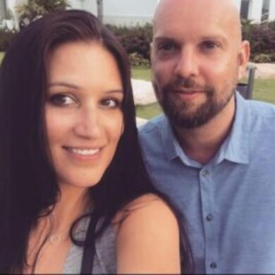 Lewis and his partner Joanna smile at the camera.