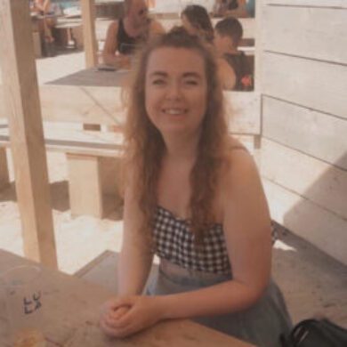 Picture of Caroline smiling at the camera with a wine glass in her hand.