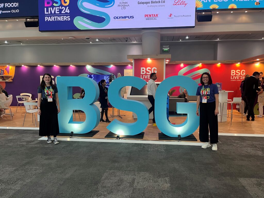 Two of our team members, Amy and Cherylyn, are stood in front of standalone "BSG" letters at BSG Live, a medical conference, in 2024.