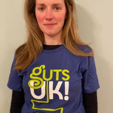 Dr Morven Allan is wearing a Guts UK t shirt and smiling at the camera.