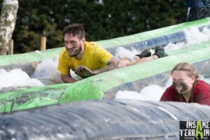 Ian is sliding down the water slides face forward at Insane Terrain. He is smiling and wearing a yellow top.