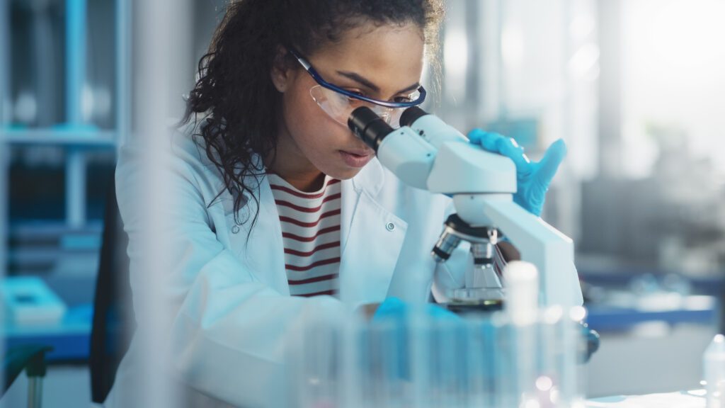 A scientist looks into a microscope.