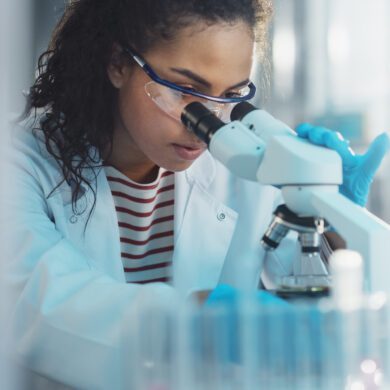 A scientist looks into a microscope.