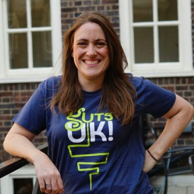 Katie is smiling at the camera and wearing a Guts UK t-shirt.