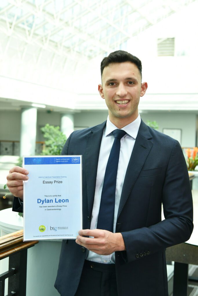 Dylan is holding his awards certificate and is smiling at the camera