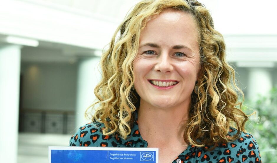 Leah holds her awards certificate and is smiling at the camera