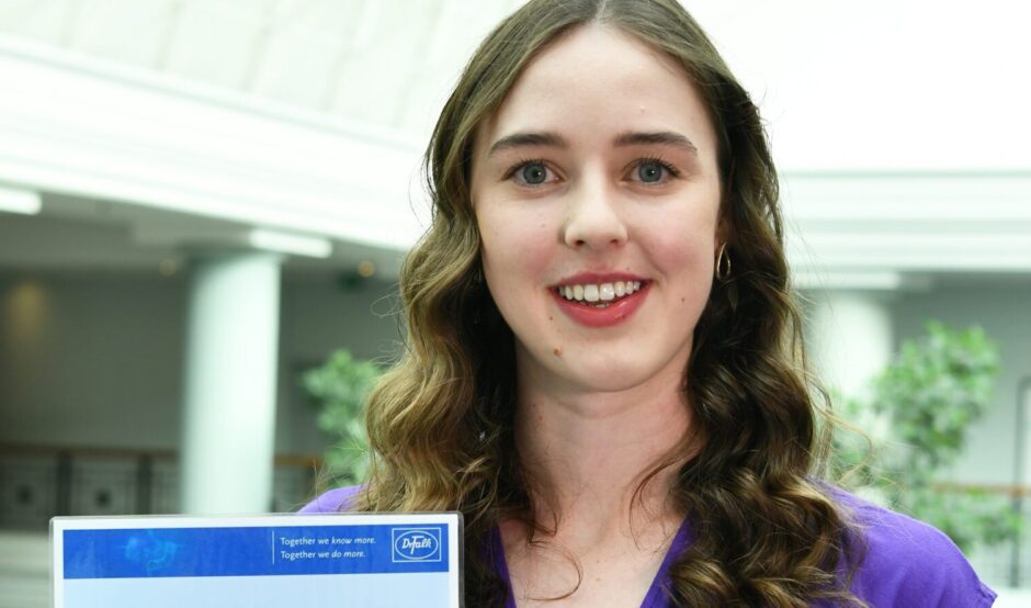Lydia holds her certificate and is smiling at the camera.