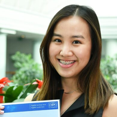 Meryl holds her certificate and is smiling at the camera.