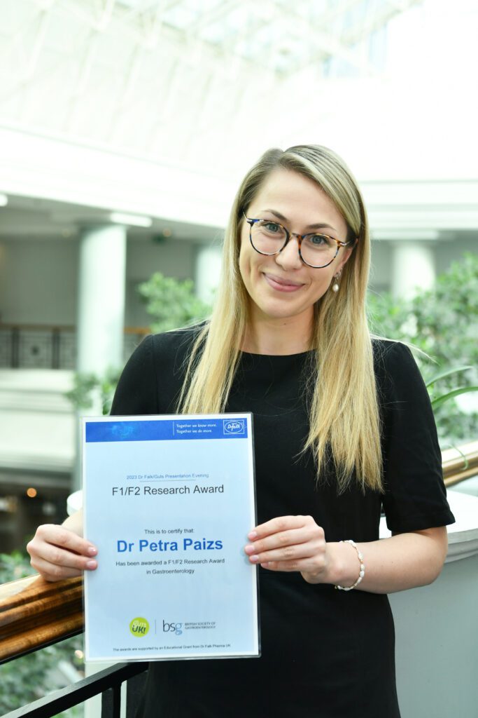 Petra is holding her awards certificate and is smiling at the camera