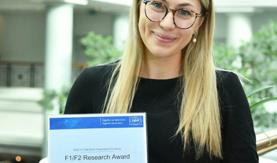 Petra is holding her awards certificate and is smiling at the camera