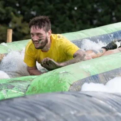 Ian is taking part in an outdoor sports event. He is on a water slide, surrounded by bubbles.