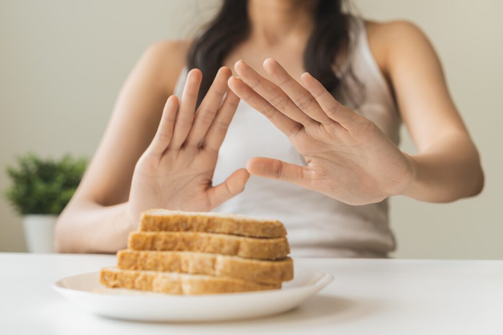 A woman's hands are raised in front of a plate of bread, indicating she does not want it.