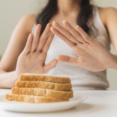 A woman's hands are raised in front of a plate of bread.