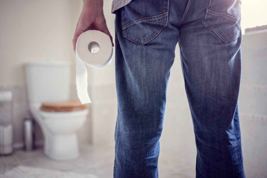 A person holding a roll of toilet paper as they stand in the bathroom.