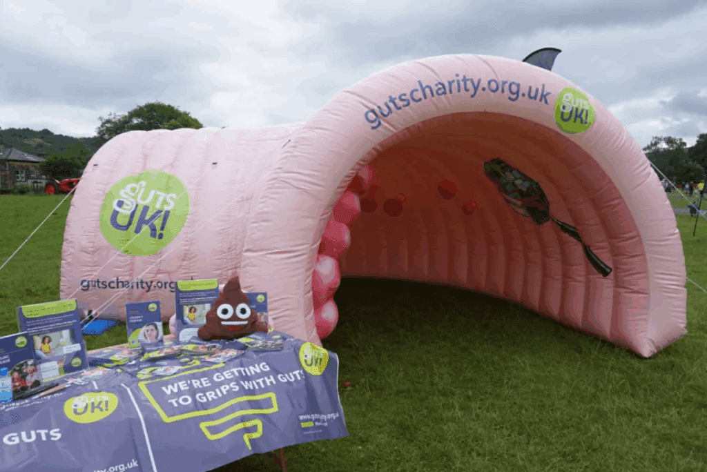 A pink, giant inflatable colon, named Colin, next to a Guts UK information stand.