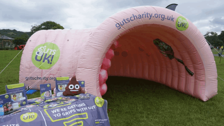 A pink, giant inflatable colon, named Colin, next to a Guts UK information stand.