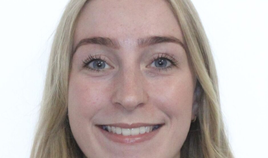 A passport photo of Lucy. She has long, blonde wavy hair and is smiling.