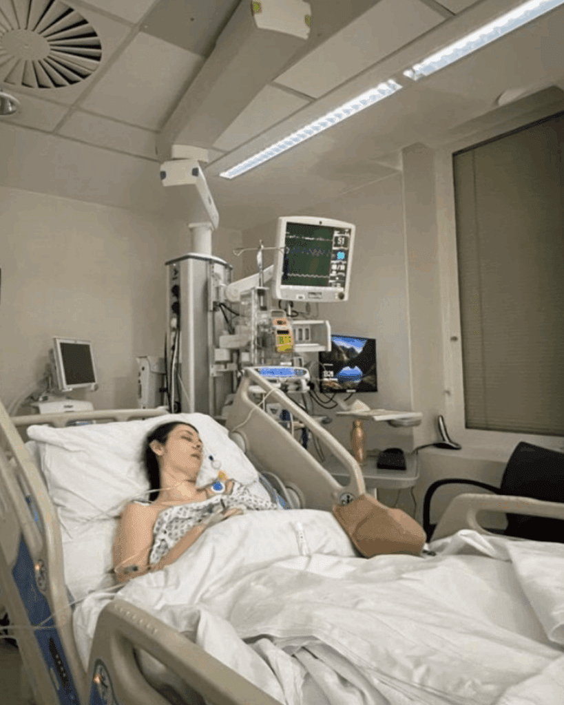 Jessie is asleep in a hospital bed surrounded by various machines.