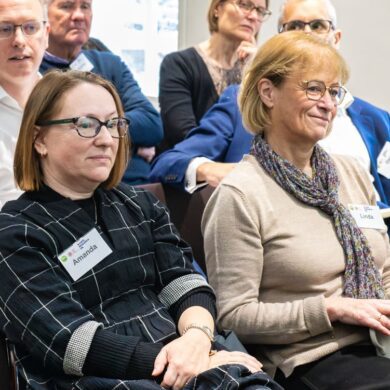 Two patients sit together in an audience, listening to someone speak.