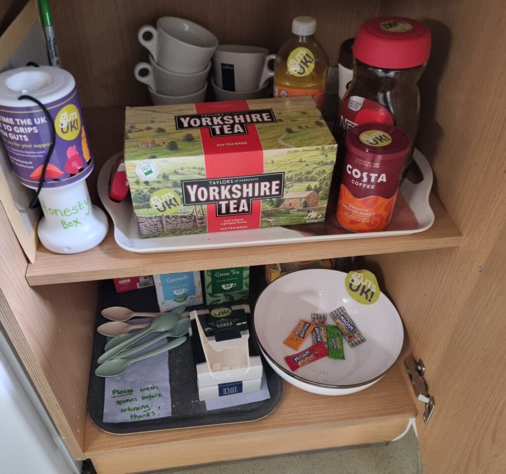 An open kitchen cupboard full of tea and coffee. 