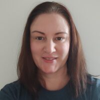 Marta is smiling at the camera and wearing a Guts UK t-shirt.