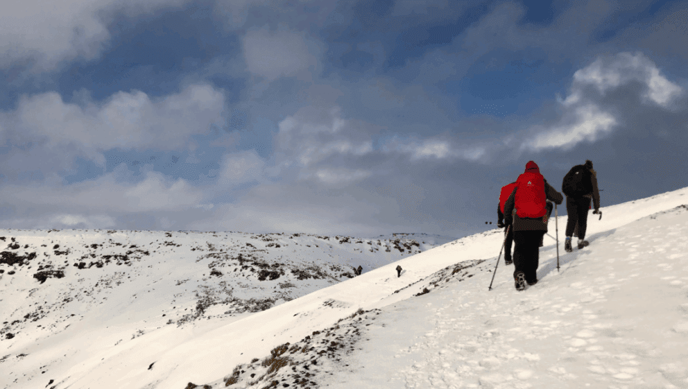 Two people trekking through snowy mountains.