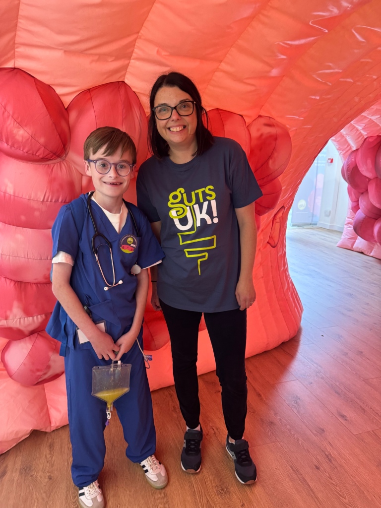 Guts UK supporter and Cherylyn stand inside Colin the giant, inflatable colon, smiling. 