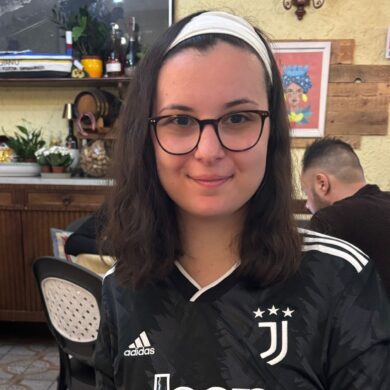 Sophia wearing a black Juventus top and glasses, smiling in a restaurant.