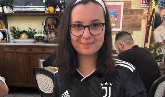Sophia wearing a black Juventus top and glasses, smiling in a restaurant.