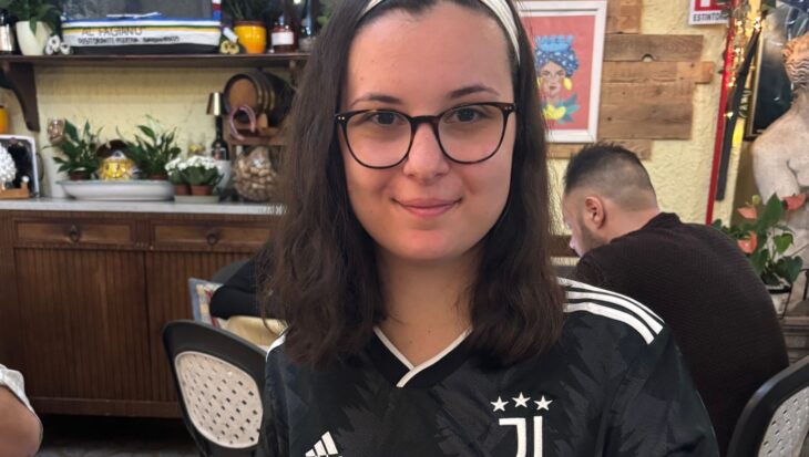 Sophia wearing a black Juventus top and glasses, smiling in a restaurant.