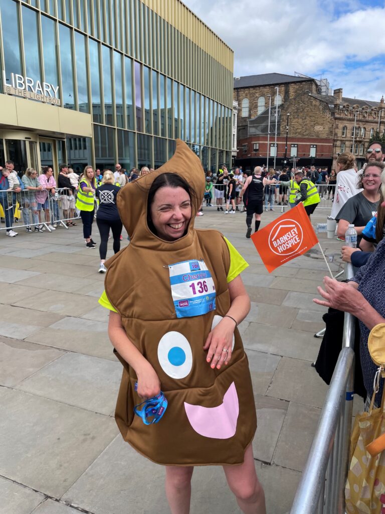 Cherlyn has just finished a 10k race and stands smiling, in a poo costume, as friends and family cheer her on.