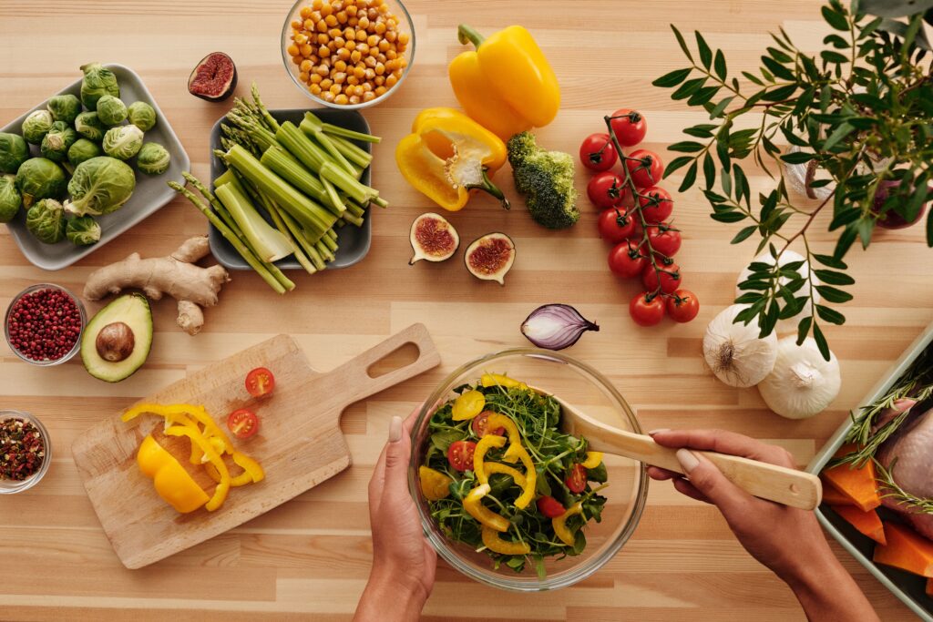 Top view of fresh vegetables and salad preparation on a wooden table.
