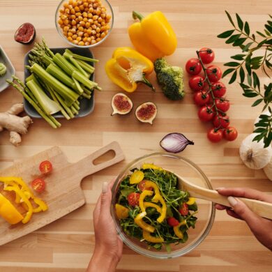 Top view of fresh vegetables and salad preparation on a wooden table.
