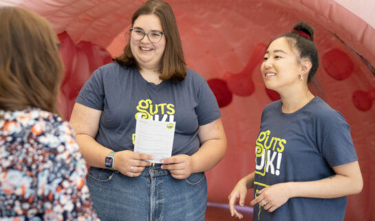 Two Guts UK team members speaking to a supporter at an event.