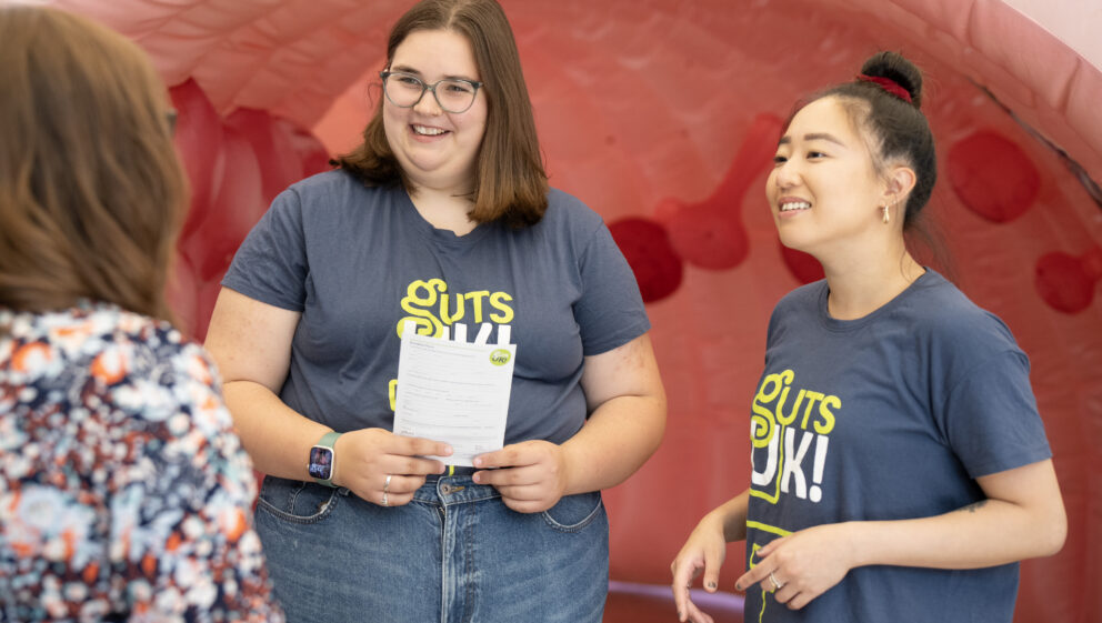 Two Guts UK team members speaking to a supporter at an event.