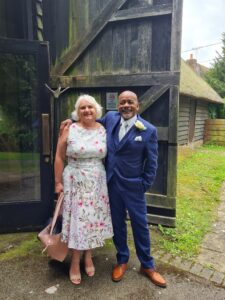 Annie, who has diverticular disease, is pictured smiling with her husband at a family wedding. They are both dressed smartly and Annie's husband has his arm around her, looking into the camera.